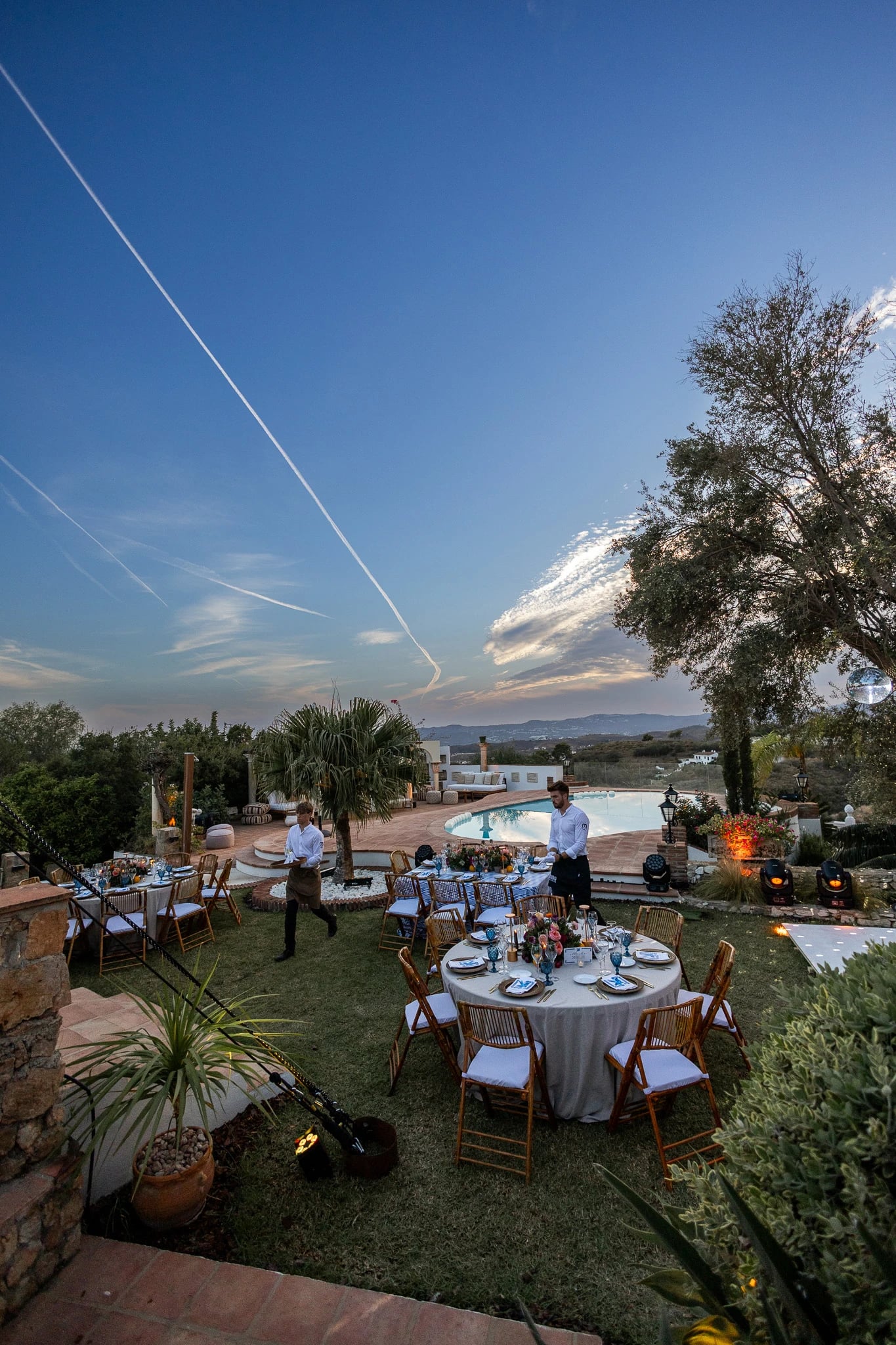 Cena privada montada en el jardín de una villa al atardecer