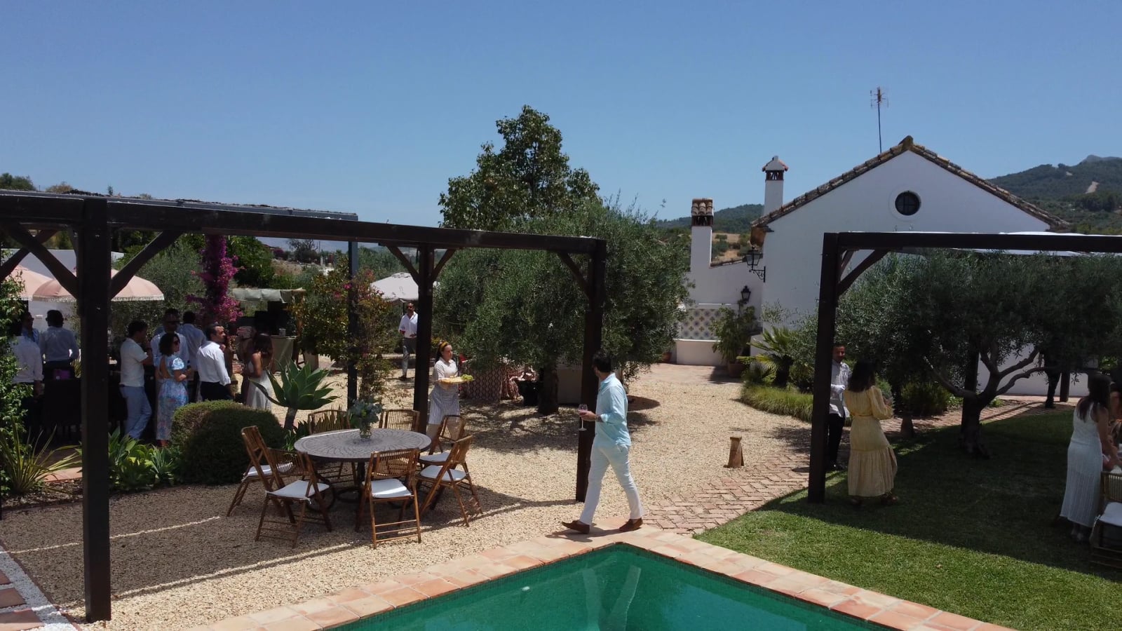 Welcome cocktail at Finca Esencia de Rosa: guests and service among the pergolas, beside the pool and the olive trees